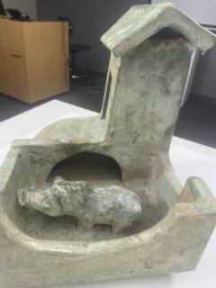 The sty of a green structure with a closeup of the carved pig that stands within.